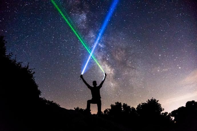 man holding green and blue flashlights